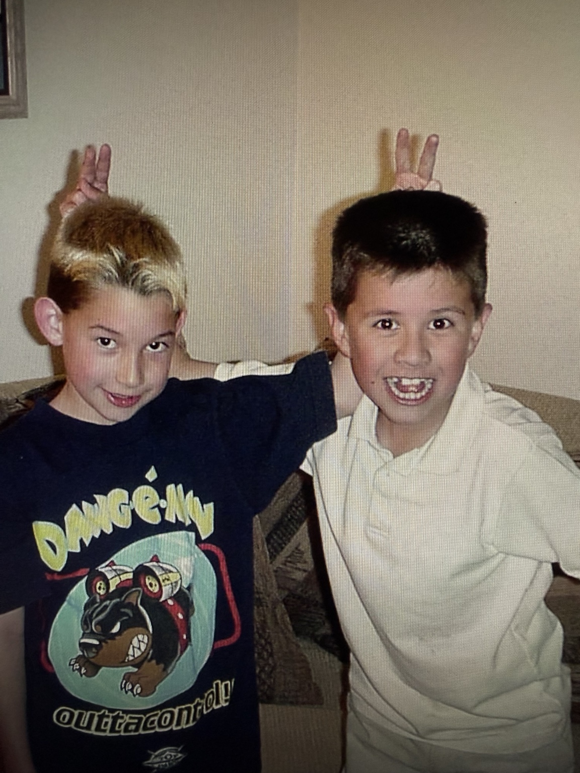 Nathan and August as children, smiling together and making bunny ears