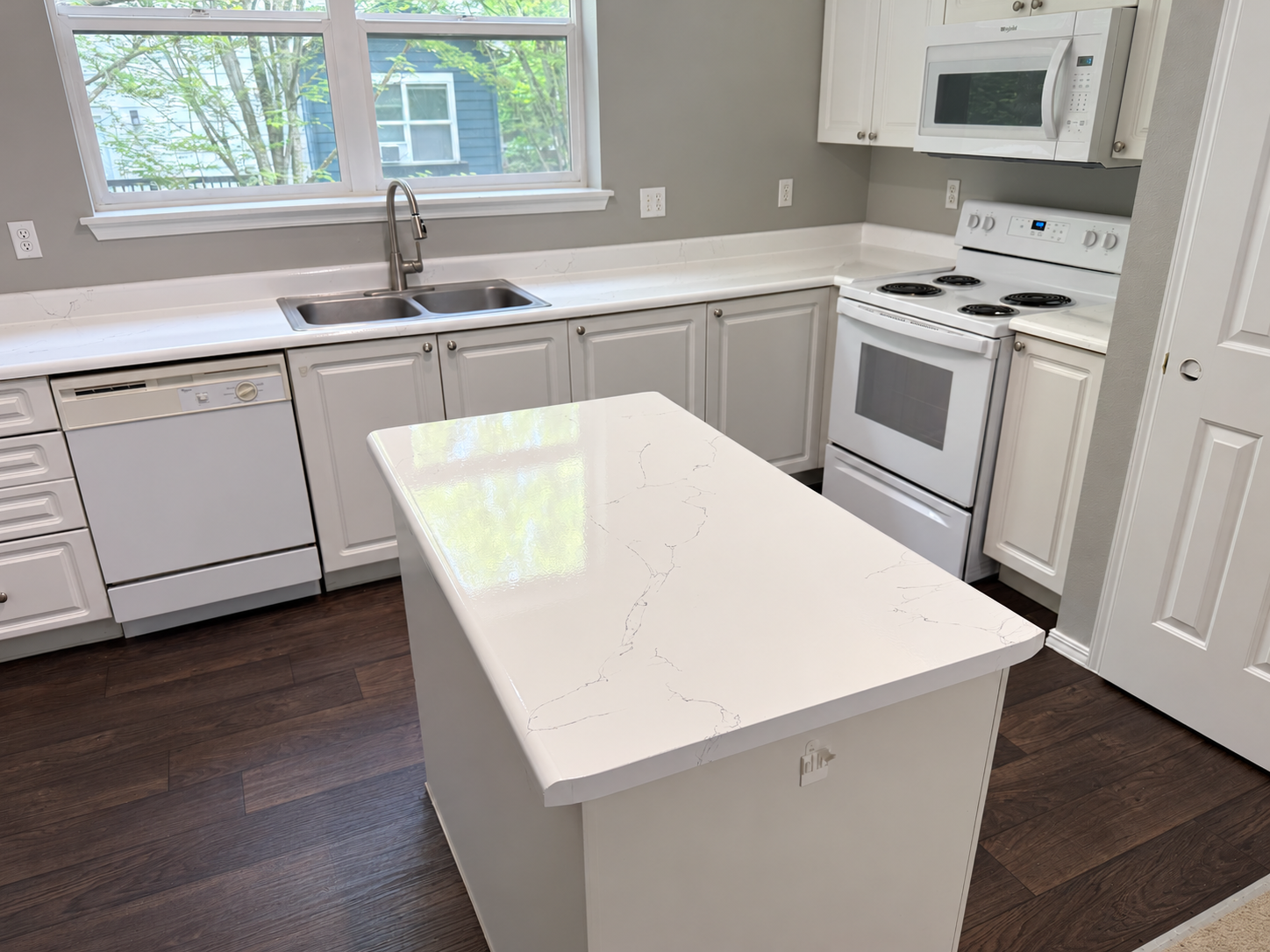 KPX white marble-look countertops and island in a bright apartment kitchen